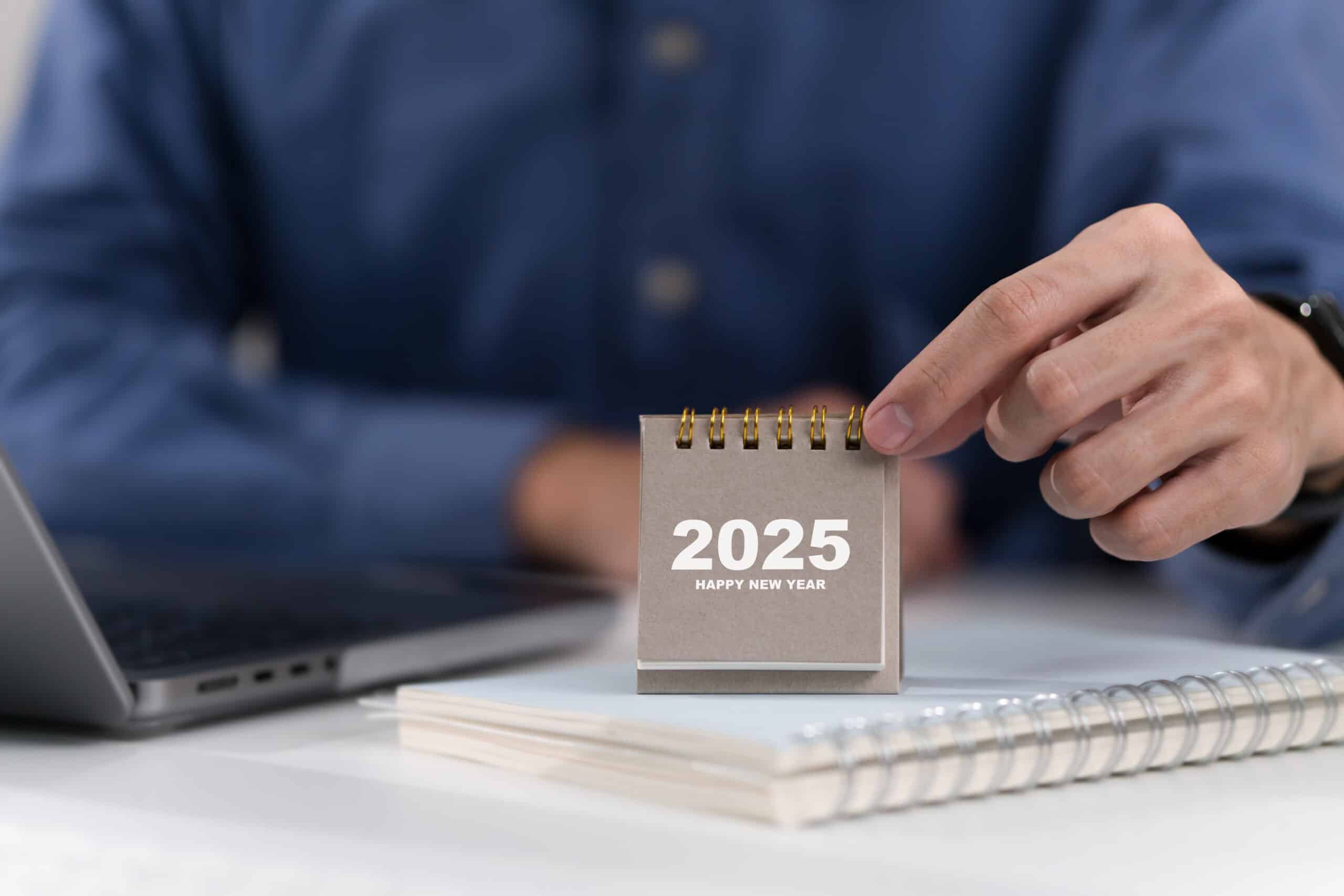 man holding 2025 calendar at his desk